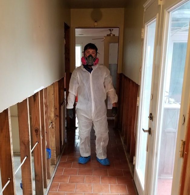 Professional mold remediation technician in protective gear inside a Houston property
